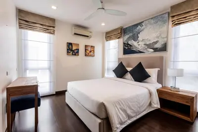 a bedroom with a bed and a desk and windows at Laguna Park Modern Pool Villa in Phuket Town