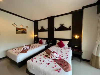 two beds in a hotel room with red pillows on them at Patong Heaven in Patong Beach