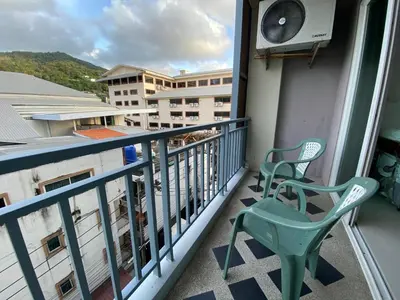 a balcony with a green chair and a building at 77 Patong Hotel & Spa in Patong Beach