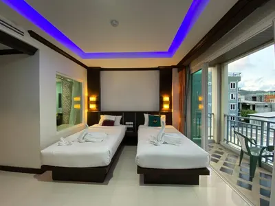 two beds in a hotel room with a balcony at 77 Patong Hotel & Spa in Patong Beach
