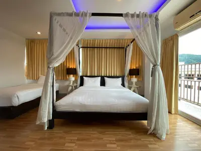 a bedroom with two beds and a large window at 77 Patong Hotel & Spa in Patong Beach