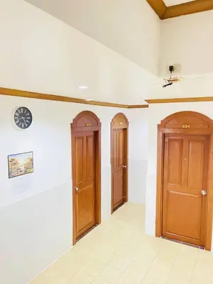 two wooden doors in a room with white walls at Innarm House Patong in Patong Beach