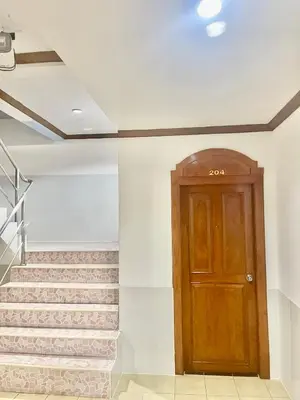 a hallway with a wooden door and stairs at Innarm House Patong in Patong Beach