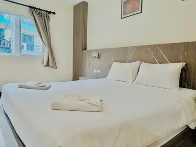 a white bed with two towels on top of it at Cocoon Patong Hotel in Patong Beach