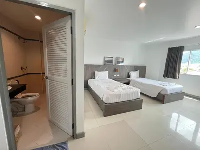 a bedroom with two beds and a toilet at Cocoon Patong Hotel in Patong Beach