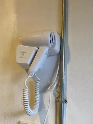 a tan hairdryer hanging on a wall at Blue Flow Hostel in Phi Phi Don