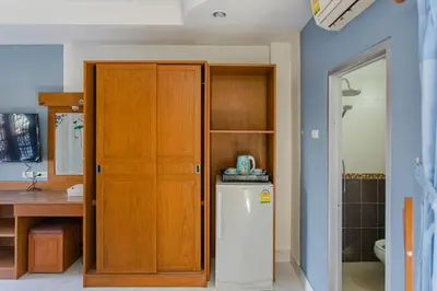 a kitchen with a wooden cabinet and a refrigerator at Pailin Hill Hotel Patong in Patong Beach