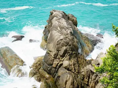 a rocky shoreline with the ocean and blue water at Patong 4BD sea view BOOM party&cozy pool villa in Ban Nakhale