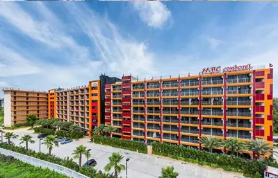 an apartment building with red and orange windows and palm trees at Квартира in Mai Khao Beach