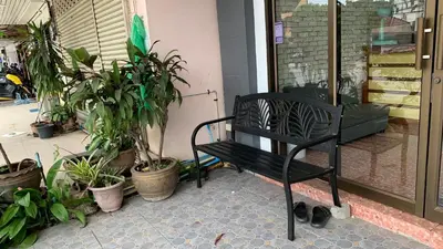 a black bench sitting on a patio with plants at Kamalaburi Guesthouse in Kamala Beach