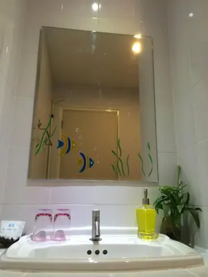 a mirror above a sink with two glasses and a bottle at Glitter House Phuket in Kata Beach
