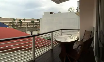 a balcony with a table and chairs on a building at Glitter House Phuket in Kata Beach