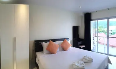 a bedroom with a large white bed with orange pillows at Glitter House Phuket in Kata Beach