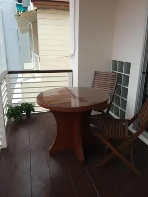 a wooden table and a chair on a balcony at Glitter House Phuket in Kata Beach