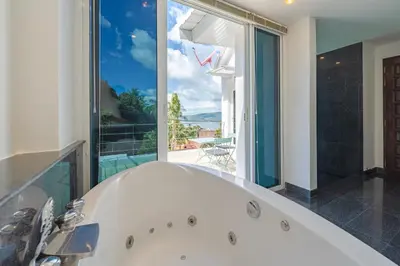a bath tub in a bathroom with a large window at White Villa Patong in Patong Beach