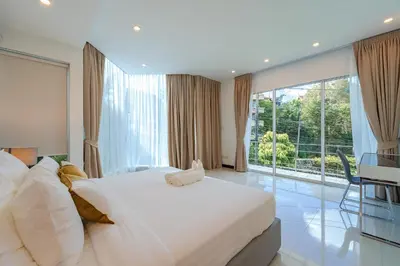 a bedroom with a large bed and a large window at White Villa Patong in Patong Beach