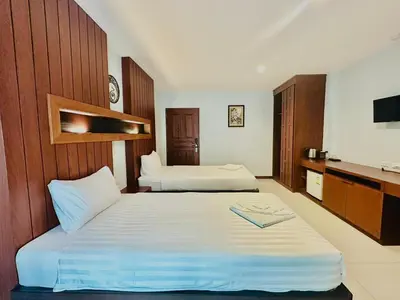 a hotel room with two beds and a television at Cokoon Deva Patong Hotel in Patong Beach