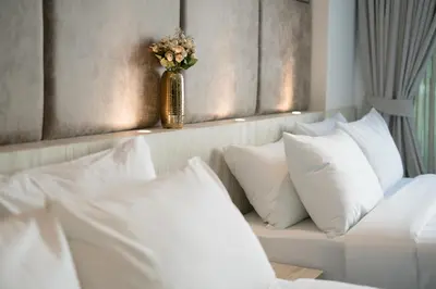 a bedroom with white pillows and a vase with flowers at Destination Patong in Patong Beach