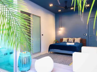 a bedroom with a blue bed and a palm tree at Contemporary 3bd Safari Pool Villa Near Nai Yang Beach in Ban Bo Han