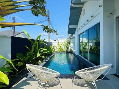 a swimming pool with two chairs next to a house at Contemporary 3bd Safari Pool Villa Near Nai Yang Beach in Ban Bo Han