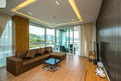 a living room with a brown couch and a tv at Sea view apartment at The Privilege by Lofty in Patong Beach