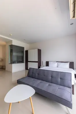a bedroom with a blue couch and a bed at Chic Condominium by Redfox Hospitality in Karon Beach
