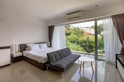 a bedroom with a bed and a chair and a window at Chic Condominium by Redfox Hospitality in Karon Beach