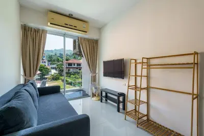 a living room with a blue couch and a tv at Chic Condominium by Redfox Hospitality in Karon Beach