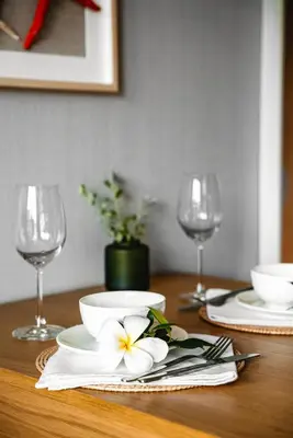 a table with two glasses and a plate with a flower on it at Title V Mountain View Pool View Gym Hammam in Rawai Beach