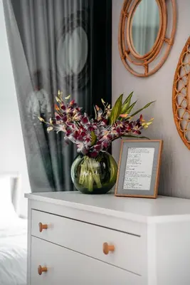 a vase with flowers on top of a dresser at Title V Mountain View Pool View Gym Hammam in Rawai Beach