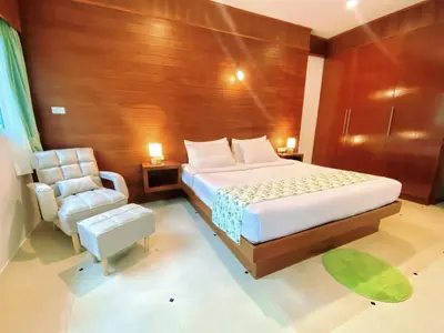 a bedroom with a large bed and a chair at Phuket Jungle Experience Resort in Karon Beach