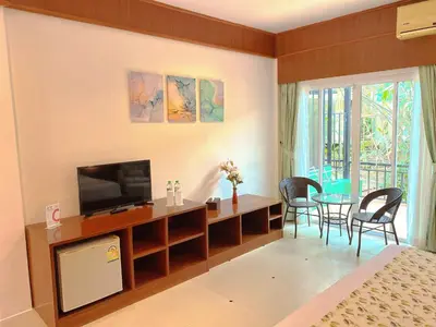 a bedroom with a television and a table and chairs at Phuket Jungle Experience Resort in Karon Beach