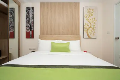 a bedroom with a large white bed with a green pillow at iCheck inn Darisa Patong in Patong Beach