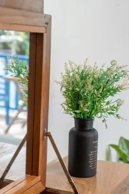 a black vase sitting on a table with a plant at Meow Cat Cafe & Hotel in Patong Beach