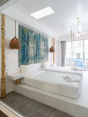 two beds in a white bedroom with a painting on the wall at Meow Cat Cafe & Hotel in Patong Beach