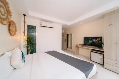 a bedroom with a white bed and a flat screen tv at Catnip Seaside Hotel&Cafe in Ban Huai Luk (1)