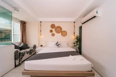 a bedroom with a large white bed and a couch at Catnip Seaside Hotel&Cafe in Ban Huai Luk (1)