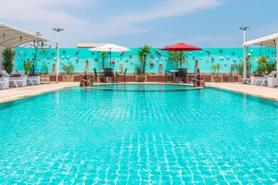 a pool at a hotel with tables and umbrellas at Sunshine Patong in Patong Beach