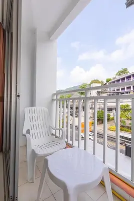 a white chair and a table on a balcony at Sunshine Patong in Patong Beach