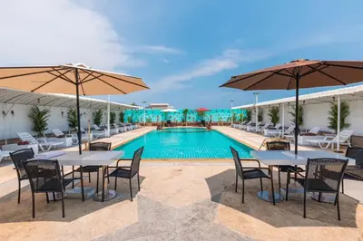 a hotel with a pool and tables and umbrellas at Sunshine Patong in Patong Beach