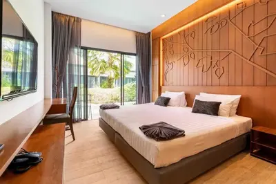 a bedroom with a large bed with a wooden headboard at Tajh Pool Villas in Chalong