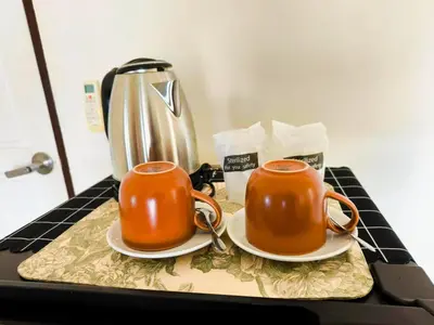 two orange mugs sitting on a table with a tea kettle at Nu Phuket Airport Resident 1 in Nai Yang Beach