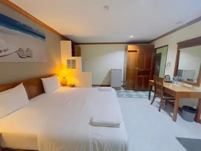 a bedroom with a large white bed and a table at Royal Vista Patong in Patong Beach
