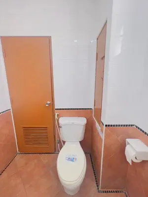 a bathroom with a toilet and a brown door at Royal Vista Patong in Patong Beach