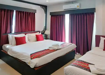 a bedroom with two beds with red curtains at Sunray Beach Hotel Patong in Patong Beach