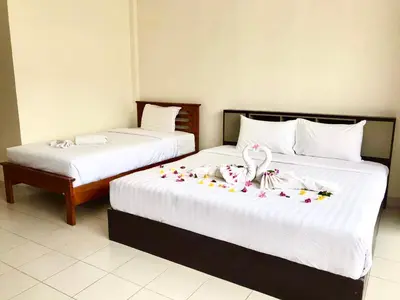 two beds in a hotel room with flowers on them at Kata Beach Guesthouse in Kata Beach