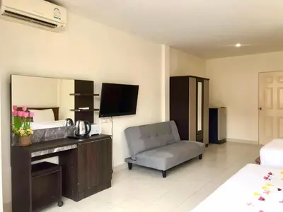 a bedroom with a bed and a chair and a television at Kata Beach Guesthouse in Kata Beach