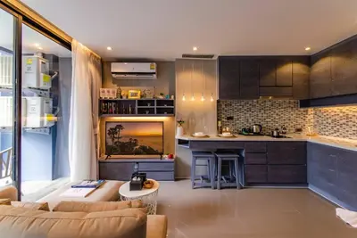 a living room with a couch and a kitchen at Kamala Beach P72 Exclusive Junior Suite in Phuket Town