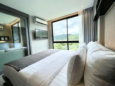 a bedroom with a large bed with a large window at Kamala Beach P72 Exclusive Junior Suite in Phuket Town