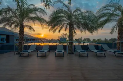 a group of chairs and palm trees on a patio at Kamala Beach P72 Exclusive Junior Suite in Phuket Town